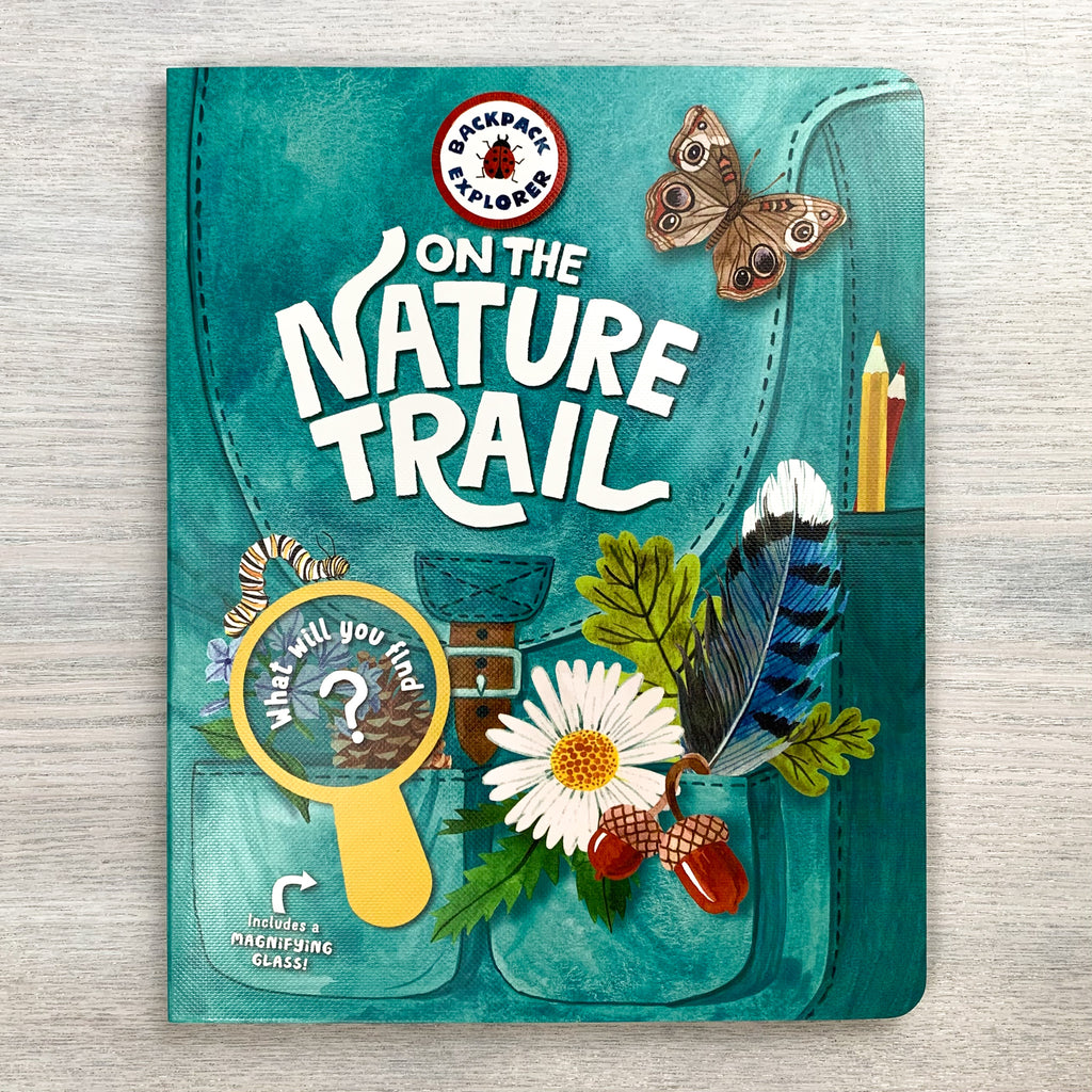 Front hardcover of On The Nature Trail showing an illustrated canvas backpack overflowing with flowers, feathers, pine cones, and acorns.