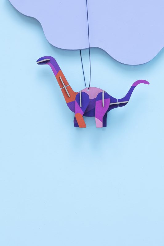 Purple and orange pop-out dinosaur ornament hanging on a purple cloud against a blue backdrop
