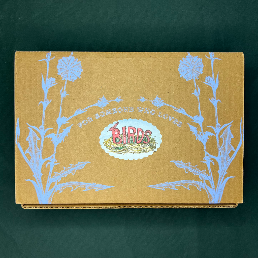 Cardboard box with floral design and 'Birds' logo on a dark green background