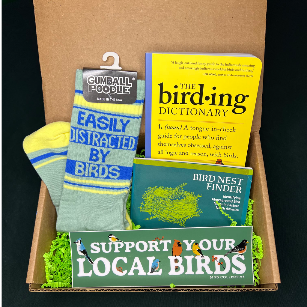 Box containing bird-themed items including socks, books, and a bumper sticker with text and graphics.