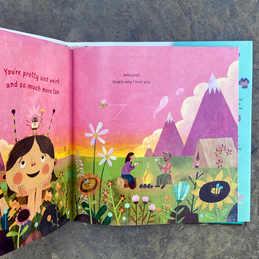 Flowers Are Pretty Weird! book opened to a page displaying an illustration of folks camping by the mountains surrounded by flowers.  A bee rests on a child's head and says "You're pretty and weird and so much more too."
