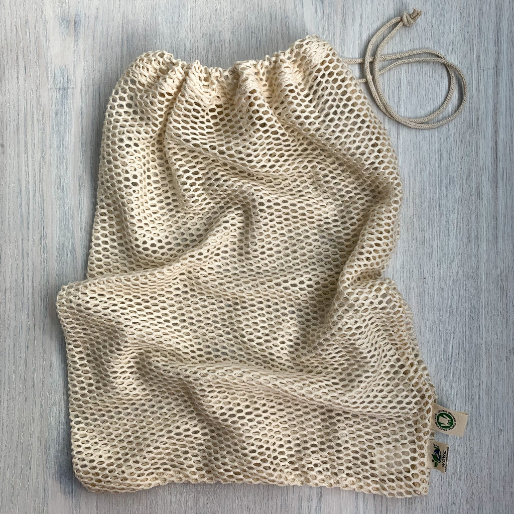 Cream-colored mesh bag on a white wood background