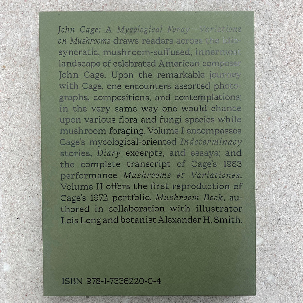 Back cover of paper case for JOHN CAGE: A MYCOLOGICAL FORAY describing the contents of the package in large black text on a plain green paper background with a pleasant texture.