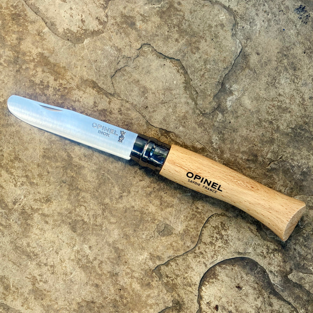 Opinel No 07 "My First Opinel" folding pocket knife shown in open position with rounded blade tip and wooden handle.