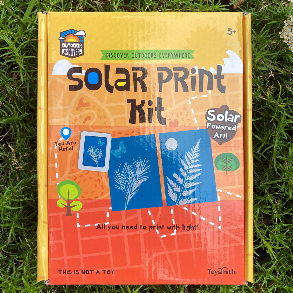 Front cover of Solar Print Kit cardboard box displaying examples of blue solar prints of ferns, leaves, and a butterfly.  