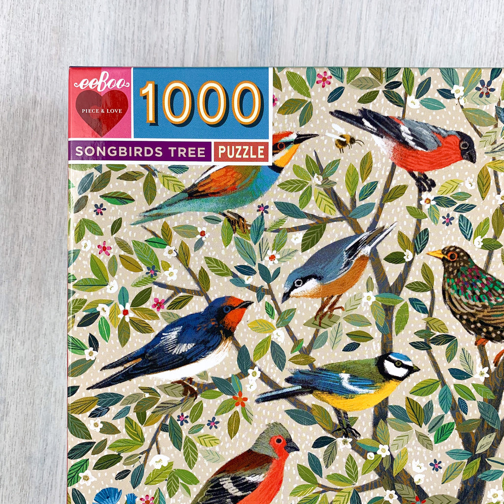 Front cover corner of Songbirds Tree puzzle box featuring many pretty illustrated birds in one small tree. 1000 pieces.