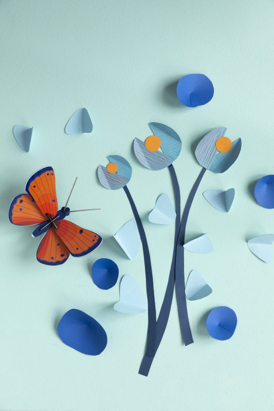 Orange butterfly wall decor on blue wall with assorted paper decorations