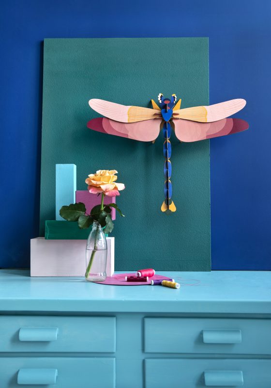 Large color-block stylized dragonfly in situ on a wall above a dresser
